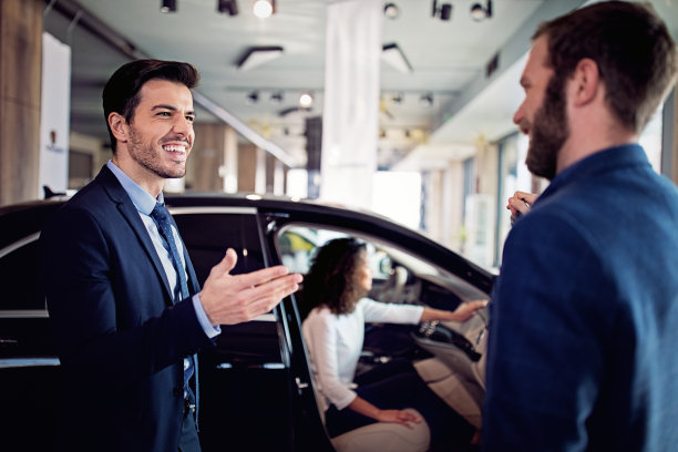 汽车经销商正在汽车陈列室向一对夫妇赠送一辆汽车图片下载