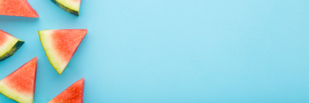 漂亮的新鲜的红色西瓜块放在浅蓝色的桌子背景上。柔和的颜色。特写镜头。甜的食品宽横幅。留出文本、引用或语录的位置。自顶向下的观点。图片下载
