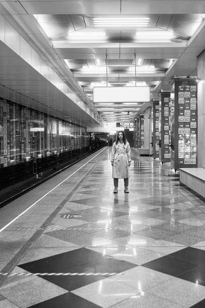 穿着米色风衣的女孩在地铁站台上等车图片下载