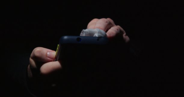 黑色背景下，人类的手正在擦拭智能手机图片下载