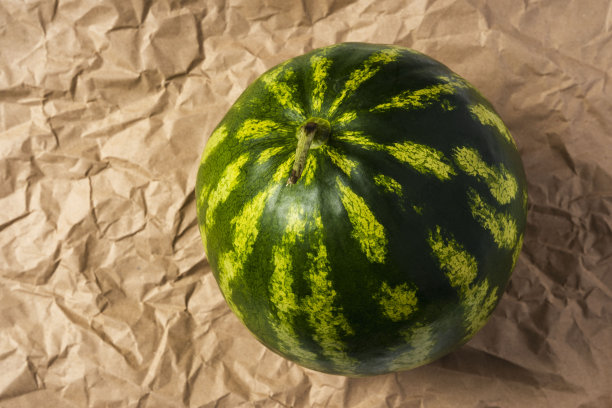 皱巴巴的包装纸背景上放着西瓜，还有复印文字的空间图片下载