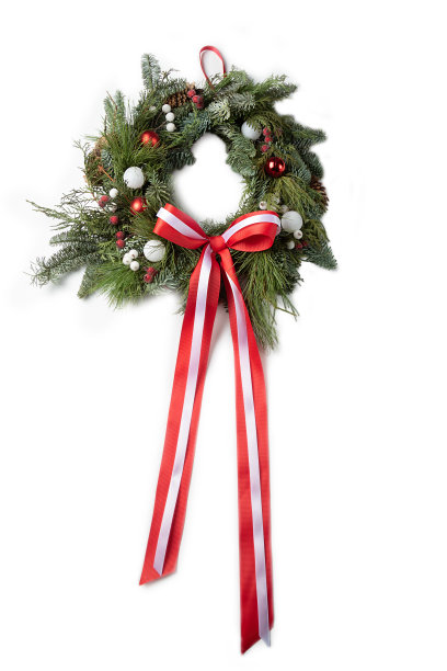 圣诞花环上有一个红色的蝴蝶结，白色的球和冰冻的浆果在浅色的木制背景上。圣诞节用红丝带装饰的花环图片下载