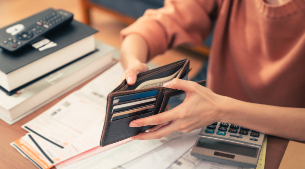 年轻女子拿着钱包，打开钱，信用卡和消费账单，计算债务账单每月在家里的桌子上。图片下载