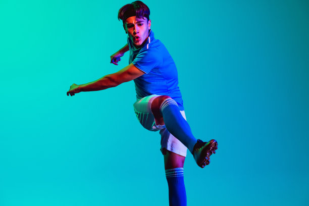 一名职业年轻男子足球运动员在蓝色背景下训练图片下载