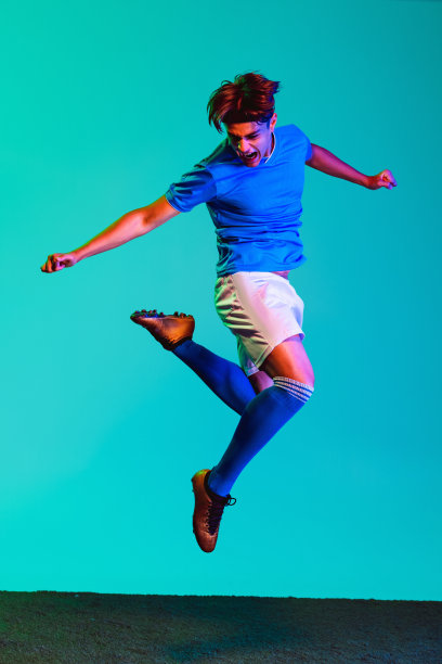 年轻男子的全身肖像，足球运动员在运动训练孤立在蓝色背景。在跳图片下载
