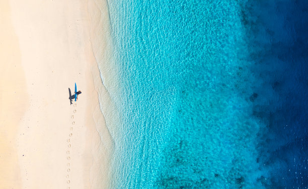 在海滩上冲浪的人。夏天蔚蓝的海水和干净的海滩。鸟瞰海景娱乐和积极的运动。图片下载