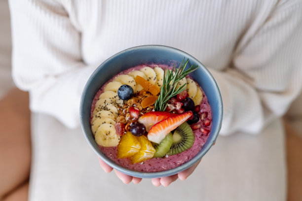 一个女人拿着健康的蓝莓奶昔碗，上面有各种水果图片下载