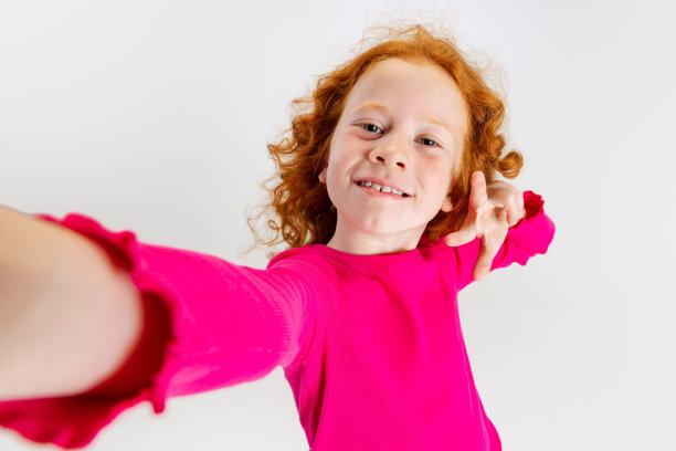 小白人女孩的肖像，孩子的姿势和自拍孤立在灰色的工作室背景。图片下载