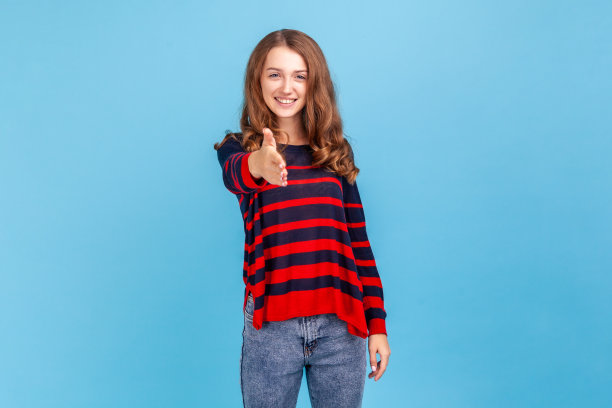 满意满意的年轻女子的肖像穿着条纹休闲风格的毛衣，伸出手，在工作面试握手。图片下载