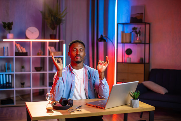 一个非洲人坐在家里的书桌前，闭着眼睛和双手禅坐图片下载