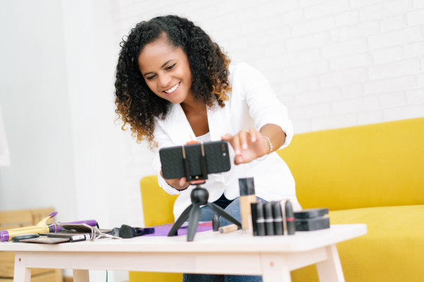 影响者快乐的年轻非洲裔美国女孩视频博主或博主录音开始视频博客告诉如何变得美丽，做一个化妆教程。社交媒体营销直播概念蒸腾。图片下载