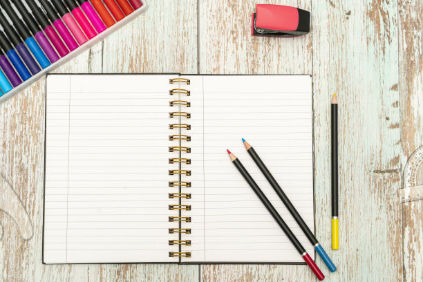 最上面的桌面物品，一个有彩色铅笔、订书机、尺子和彩色马克笔的时尚笔记本。图片下载