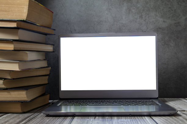 桌上一堆书旁边放着一台打开的笔记本电脑图片下载