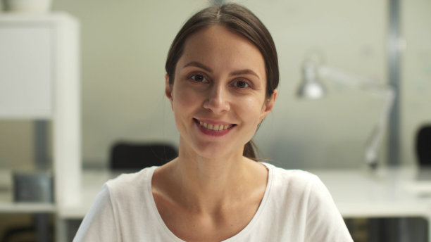 一个年轻的，愉快的，微笑的女人看着相机的特写镜头图片下载