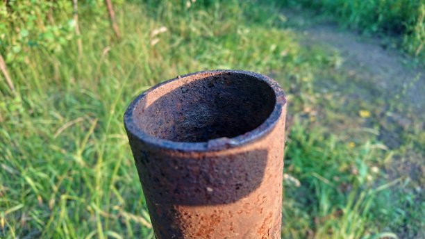 生锈的管子割在绿草的背景上图片下载