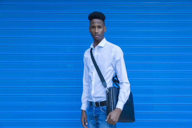肖像非洲裔美国商人，白色衬衫和公文包在蓝色背景图片下载