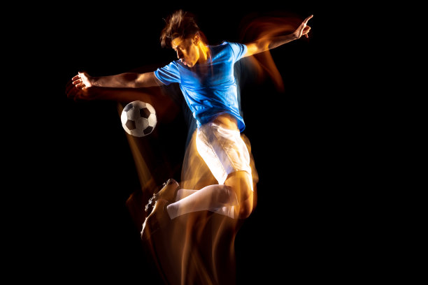 年轻的运动员，足球运动员训练孤立在黑色背景混合光。后卫图片下载