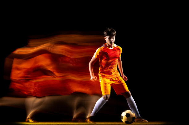 年轻运动员的肖像，足球运动员训练孤立在黑色背景混合光。摩天观景轮图片下载