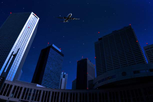 在夜间飞过摩天大楼的飞机。图片下载