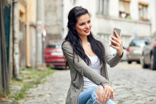 年轻可爱的女性在街上使用智能手机。图片下载