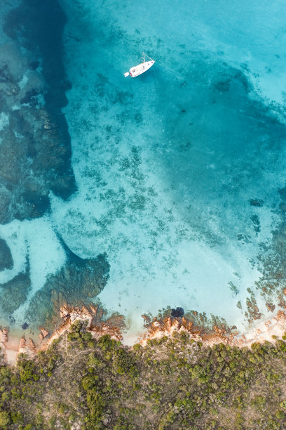 从上面看，令人惊叹的鸟瞰图，绿色和岩石海岸线与帆船航行在蓝绿色，水晶般清澈的水。Liscia Ruja, Costa meralda，意大利撒丁岛。图片下载