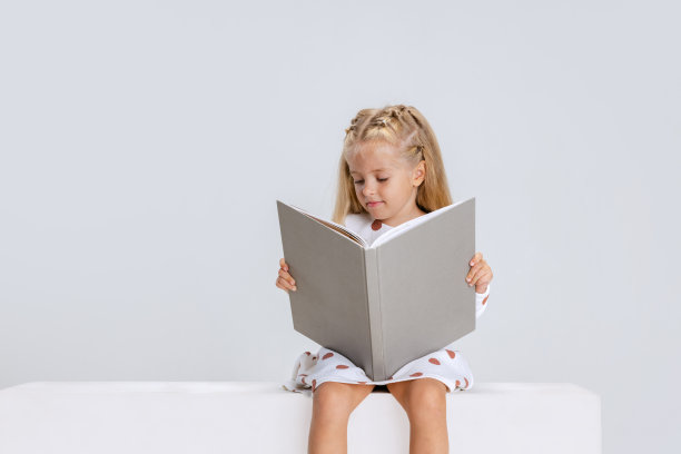 学前班的小女孩带着书在白色的工作室背景下摆出孤立的姿势。图片下载