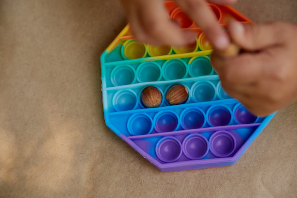 幼儿玩的pop it玩具和榛子。运动技能发展的游戏。彩虹触摸感官的烦躁。前视图。高质量的照片图片下载