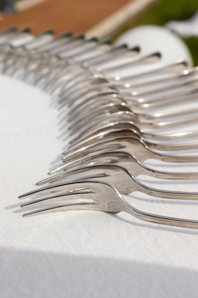 在夏天的假日里，餐桌上白色背景上放着一排叉子图片下载