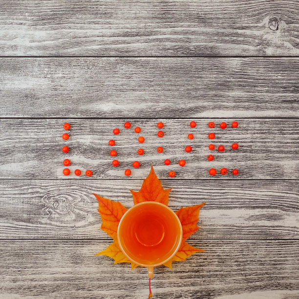 红色浆果、茶杯和枫叶组成的“爱”字，木质背景，顶部视角，方形图图片下载