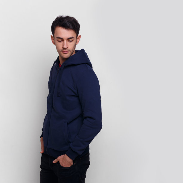 年轻男子穿着深蓝色的毛衣和牛仔裤，双手插在口袋里，向下看，孤立的白色背景。图片下载