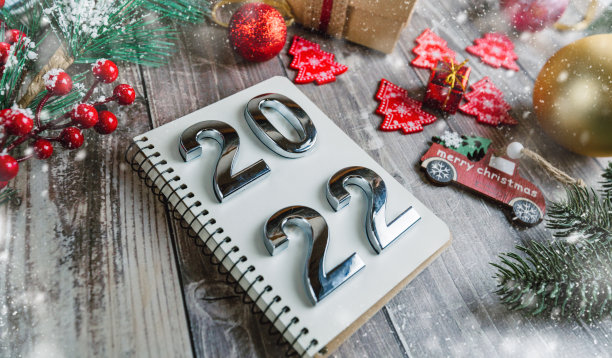 木制背景上有圣诞装饰和雪花的螺旋记事本上写着数字2022。图片下载
