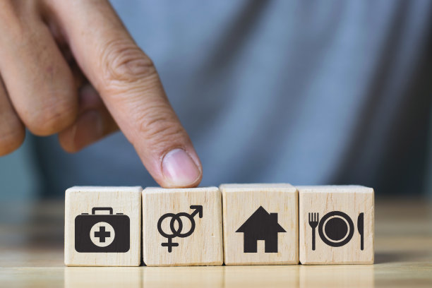 人的手摆放立方体有衣食住药四个基本的人类需求概念。图片下载