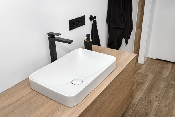 浴室里有一个现代的洗手池，有一个哑光黑色的龙头，地板上铺着模仿木头的瓷砖。图片下载