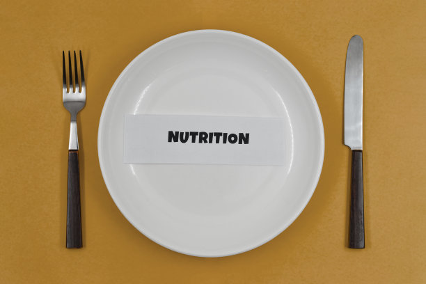 概念性照片，桌上摆着一个空盘子，棕色背景上是健康生活的原则之一——“营养”图片下载