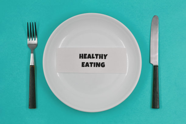 概念性照片，桌上摆着一个空盘子，绿松石背景上的健康生活原则之一——“健康饮食”图片下载