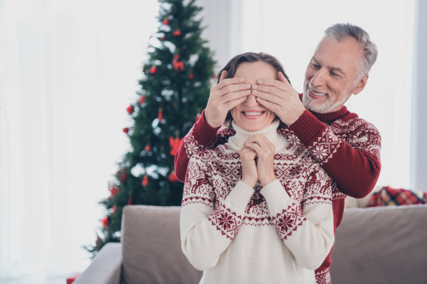 一对甜蜜夫妇的照片，老夫人男人闭着眼睛在家里穿毛衣图片下载