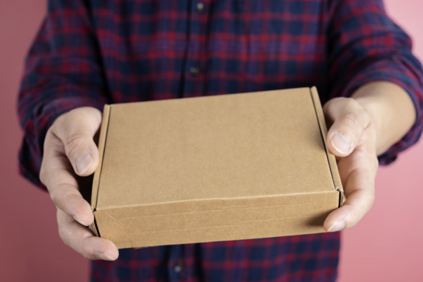 快递员拿着带有标签和复印空间的硬纸板包裹。图片下载