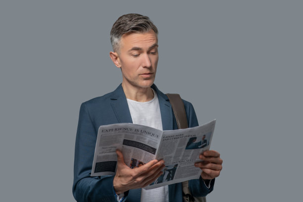 感兴趣的优雅男子在演播室里看报纸图片下载