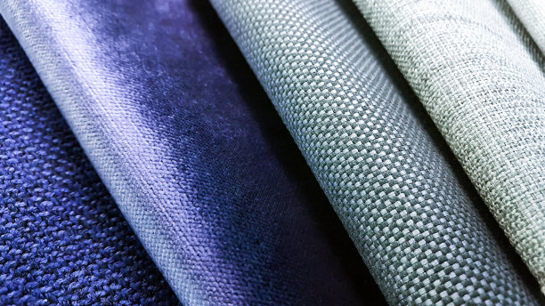 窗帘或窗帘织物的样品。生产用于家具装饰的软垫、细部。微距视图照片，选择性聚焦在灰色织物纹理。灰色和蓝色天鹅绒面料样品。图片下载