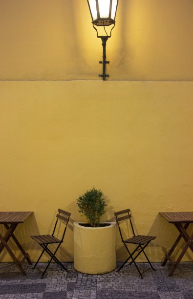 捷克布拉格，咖啡桌和椅子，背景是明黄色的墙图片下载