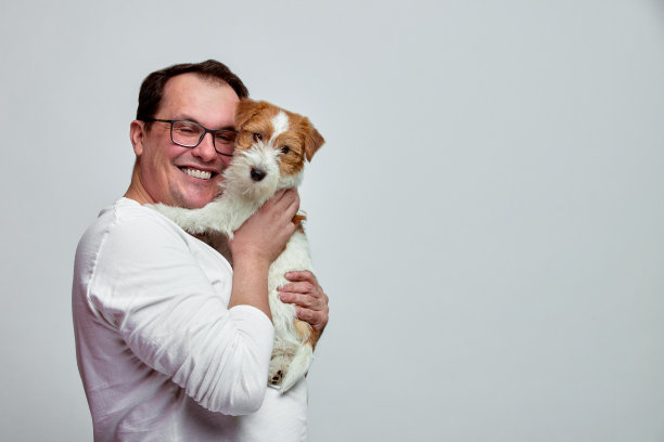 狗躺在主人的肩膀上。杰克罗素梗在他的主人手中的白色背景。人与动物的概念。T图片下载