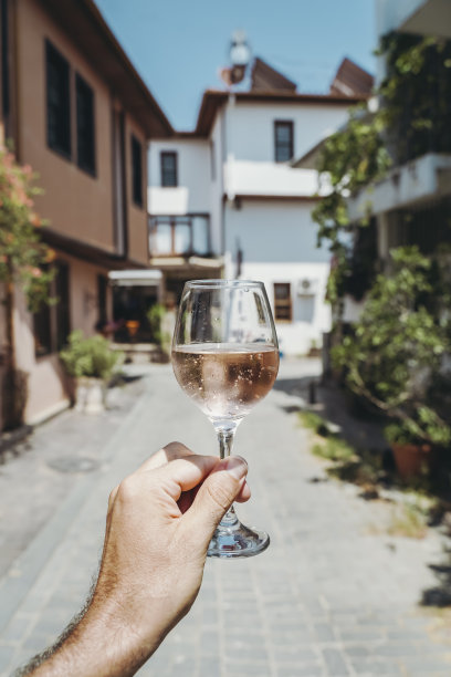 手里拿着一杯酒。夏日阳光下，地中海海滨旅游小镇的夏日咖啡馆里，一杯新鲜的玫瑰红葡萄酒映衬着夏日的阳光。夏日，旅行，生活方式，放松，享受的概念。图片下载