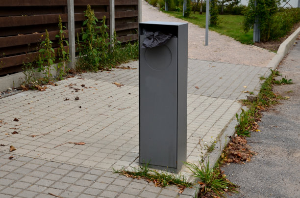 在垃圾桶的金属柱子上放置狗屎袋的细节。一只被激光板烧伤的狗。街道，公园旁的人行道图片下载