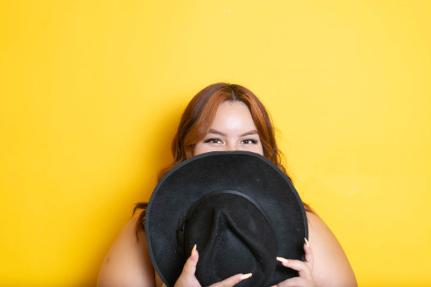 红发大码模特用软呢帽遮住脸的创意肖像图片下载