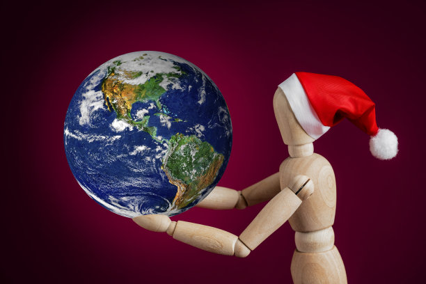 世界，圣诞快乐!!木制假人戴着圣诞帽，手持地球仪(美国视角)图片下载