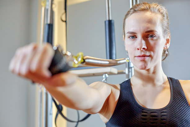 体操女人普拉提伸展运动在改革家床教练女孩。穿着紧身连衣裤练习普拉提的健康微笑女人。有选择性的重点图片下载