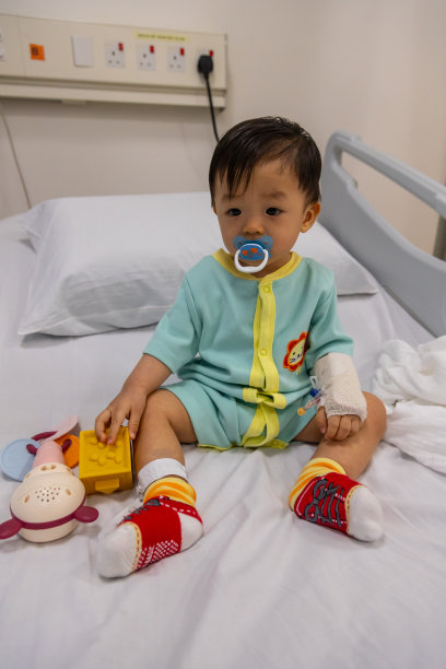 生病的婴儿在病床上玩他的玩具。图片下载