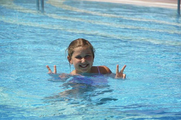 在游泳池游泳的小女孩：享受暑假图片下载