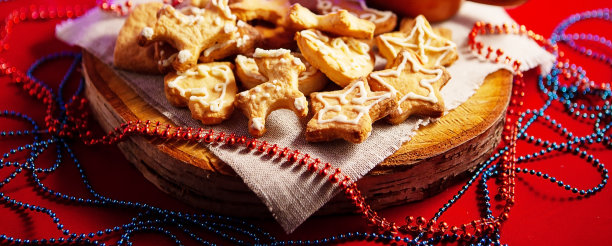 圣诞姜饼饼干，木勺里有新鲜的浆果，放在木架上，红色背景上有一个美丽的焦景发光的花环，大景深，选择性聚焦。图片下载