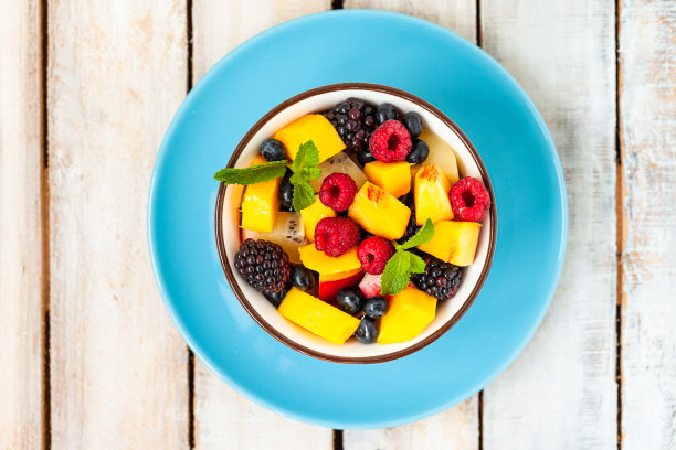 低卡路里美味甜点的概念。夏季新鲜的水果沙拉碗。健康的天然有机食品。美味的小吃，简单的美味的午餐。关闭木制背景平铺俯视图图片下载